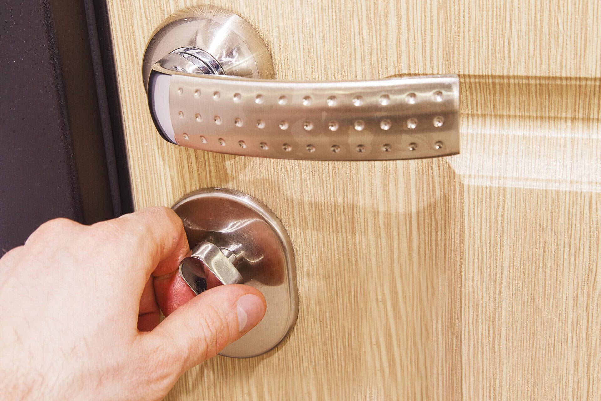 The man's hand closes the lock on the door.