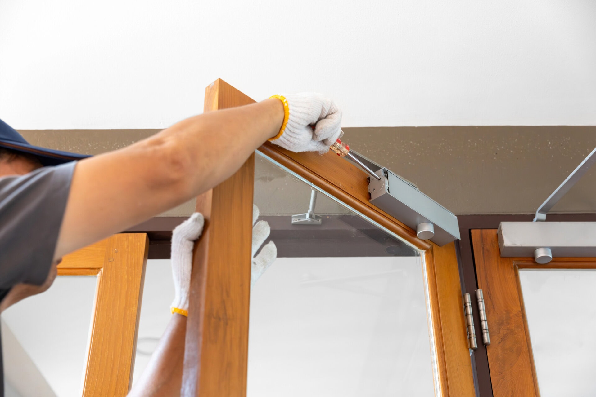 Handyman fixing door closer and adjust hydraulic arm extended